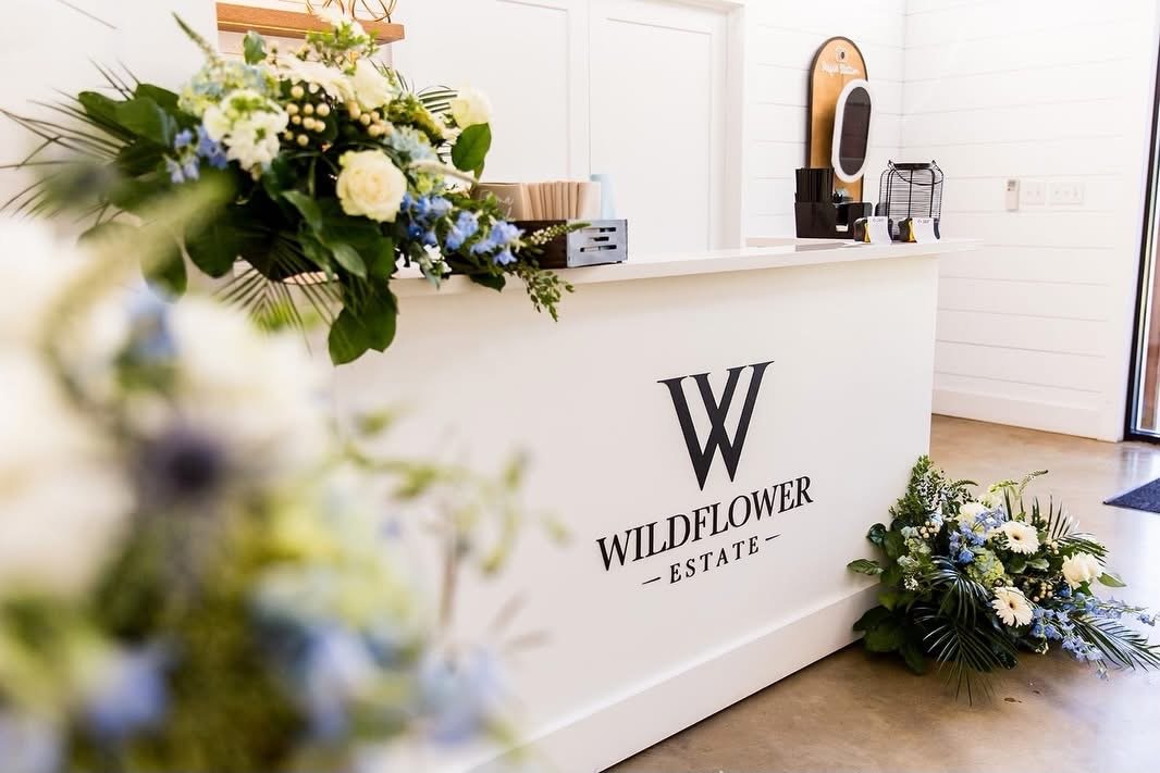 The custom-built white bar with granite top and the Wildflower Estate logo, dressed with white and blue florals